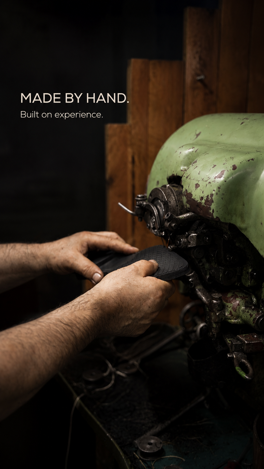 Hands guiding a black shoe upper at a sewing machine
